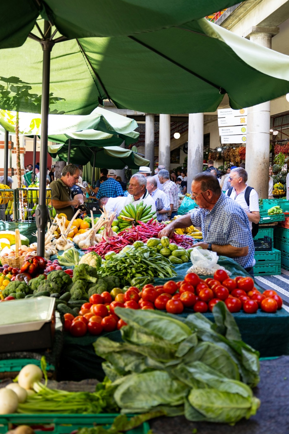 Un mercado al aire libre con puestos de fruta y verdura y gente comprando