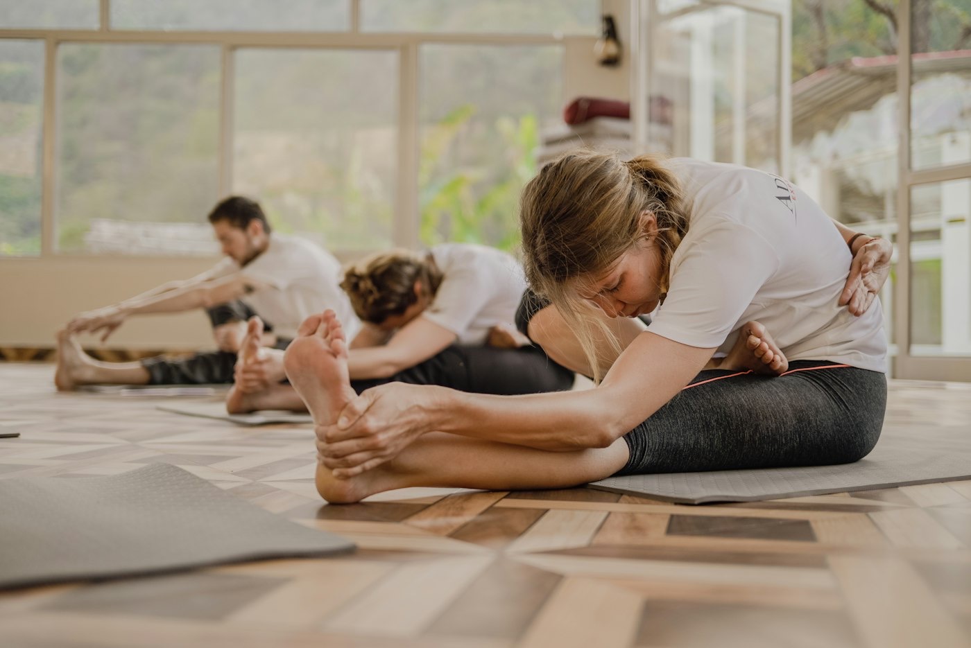 Una clase de yoga en un estudio luminoso, con varias personas estirando en sus esterillas
